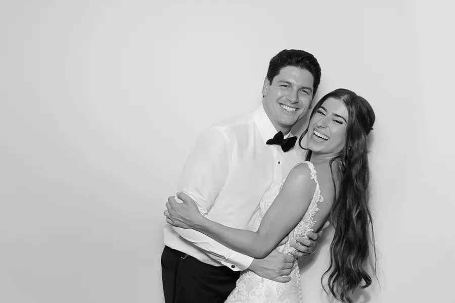 Elegant black-tie wedding guests posing in a luxury photo booth setting.